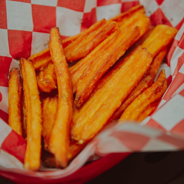 Sweet potato fries in a red and white checkered paper container at Mozillas Kitchen.