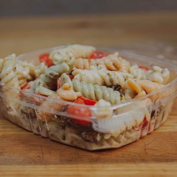 Mozillas Kitchen's Mediterranean pasta salad with colorful fusilli, tomatoes, and creamy dressing in a clear container.